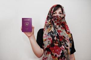Junge arabische muslimische Frau in Hijab-Kleidung hält Pass der Republik Kosovo auf weißem Wandhintergrund, Studioporträt. foto