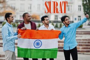 Inschrift der Stadt Surat. gruppe von vier indischen männlichen freunden mit indien-flagge, die selfie auf handy machen. Konzept der größten indischen Städte. foto