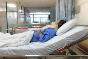 verschwommen, frau nach der operation schläft auf einem bett im krankenhaus. foto