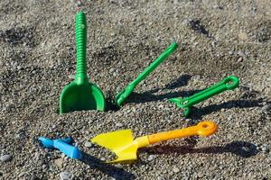 Kinderspielzeug an der Küste, bunte Schaufeln, Schaufeln und Rechen liegen an einem felsigen Strand. Kindersicherheitskonzept. foto