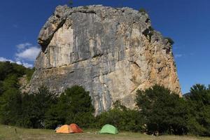 drei bunte Touristenzelte vor dem Hintergrund einer Felsspitze. das konzept von outdoor-aktivitäten und klettern. foto