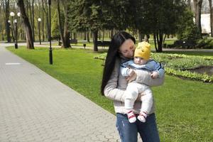 eine schöne, junge, attraktive mutter mit einem kleinen jungen-sohn geht im frühlingspark spazieren. foto