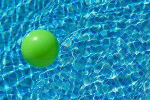 runder grüner Ball auf der Wasseroberfläche in einem Pool mit blauem Wasser und Wellen. das konzept der kindersicherheit in der nähe des wassers. foto