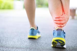 Läufer berührt schmerzhaft verdrehten oder gebrochenen Knöchel. Trainingsunfall eines Sportlers. sport lauf knöchel verstauchung verstauchung verursachen verletzung knie. und Schmerzen in den Beinknochen beim Laufen im Freien im Park. foto