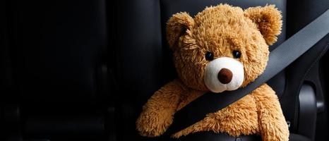 Brauner Teddybär mit Sicherheitsgurt im Auto foto