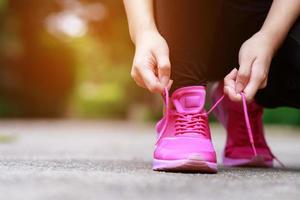 Laufschuhe rosa. Nahaufnahme einer Sportlerin, die Schnürsenkel zum Joggen auf der Straße bindet. Läufer Krawatten bereiten sich auf das Training vor. sportlicher Lebensstil. foto