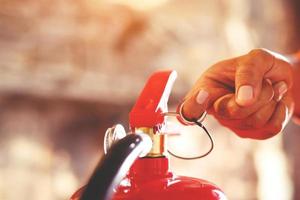 Feuerwehrmann hält Feuerlöscher in der Hand. verfügbar in Notfällen Brandschaden Hintergrund. Sicherheitskonzept. foto