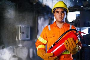 Feuerwehrmann hält Feuerlöscher in der Hand. verfügbar in Notfällen Brandschaden Hintergrund. Sicherheitskonzept. foto