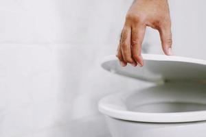 Die Hand des Mannes öffnet den Toilettendeckel foto