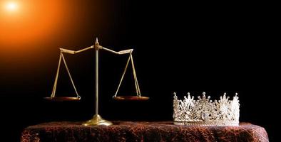 Diamond Crown of Miss Beauty Queen Pageant Contest und Scale Justice Balance sind auf schwarzem Hintergrund als Rampenlichtleck. konzept von fairness und unfair im festzugswettbewerbsgeschäft, kopierraum foto