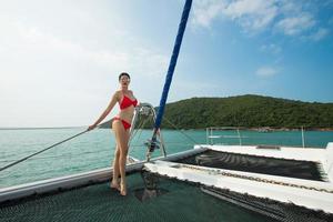 schöne asiatische Mix-Rennen gebräunte Haut Frau zu Fuß entlang Luxusyachten im tiefen Ozean, rote Bikini-Sonnenbrille Mädchen posiert als Model im Docking-Pier unter blauem Sommerhimmel im Urlaub foto