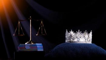 Diamond Crown of Miss Beauty Queen Pageant Contest und Scale Justice Balance sind auf schwarzem Hintergrund als Rampenlichtleck. konzept von fairness und unfair im festzugswettbewerbsgeschäft, kopierraum foto