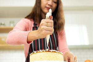 asiatische junge erwachsene frau lernen, wie man online-kurs in der küche bäckerei kuchen kocht. weibliches muttervideo zur cyberspace-klasse auf laptop als blogger-social-media-inhalt und streaming-lernen, kopierraum foto