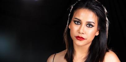 indische gebräunte haut asiatische frau zeigt gesichts-make-up mit hintergrundbeleuchtetem licht und wasserspritzerspray