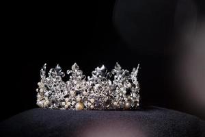 Diamant-Silberkrone für Miss-Schönheitswettbewerb, Kristall-Tiara-Schmuck verziert mit Edelsteinen und abstrakter dunkler Hintergrund auf schwarzem Samtstoff, Makrofotografie-Kopienraum für Textlogo foto