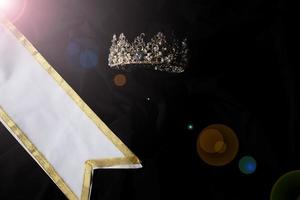 Weißgold-Gewinnerschärpe für Miss-Schönheitswettbewerb, leerer Bereich für Textgewinner-Landwort, Studiobeleuchtung abstrakter dunkler drapierender Textilhintergrund, wichtige Dekoration mit Diamantkrone foto