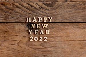 frohes neues jahr 2022. zitat aus holzbuchstaben und zahlen 2022 auf holzhintergrund. kreatives konzept für neujahrsgrußkarte foto