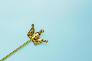 Goldener Zauberstab aus Pailletten in Kronenform auf pastellblauem Hintergrund. kreative flache lage im minimalen stil foto
