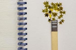 surrealer Pinsel, der goldene Sterne Konfetti zeichnet. künstlerisches konzept auf skizzenbuchhintergrund foto