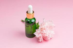 vitamin c-serum in kosmetikflasche mit nelkenblume auf rosa hintergrund. Ätherisches Zitrusöl, Kosmetik Aromatherapie. Bio-Spa-Kosmetik mit pflanzlichen Inhaltsstoffen. foto