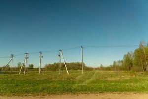 ländliche Frühlingslandschaft. Grünes Feld und Stromleitung entlang der Straße. russische ländliche Seite. foto
