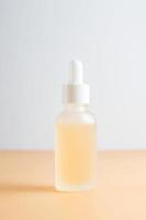 Seitenansicht einer Milchglas-Tropfflasche mit Beauty-Gesichtsöl auf beigem Hintergrund. Anti-Aging-Serum mit natürlichen Inhaltsstoffen. foto