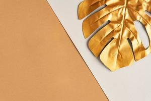 Exotischer Sommertrend im minimalistischen Stil. goldenes tropisches palmenmonsterblatt auf zweifarbigem hintergrund. glänzendes und funkelndes Design, Modekonzept. foto