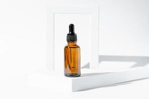 bernsteinfarbene Kosmetikflasche mit Pipette auf weißem Podium, Produktverpackung, Anti-Aging-Serum mit Peptiden, Kosmetikmodell, Spa-Konzept. foto