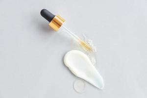 Pipette und Tropfen und Abstriche von Kosmetika. flüssiges Gel oder ein Tropfen Serum mit Gesichtscremeabstrich. natürliche Bio-Kosmetik foto