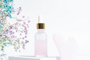 Gua Sha und feuchtigkeitsspendendes Serum auf weißem Hintergrund. Naturkosmetik und Gesichtspflege. rosenquarz schönheitsherz gua sha werkzeuge für hautpflegeroutinen. harte Schatten foto