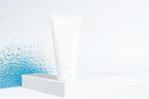 Weiße Plastiktube mit Gesichts- oder Körpercreme auf einem Podium auf blauem Hintergrund mit Farbverlauf und Kopierraum. Modell für Marken foto