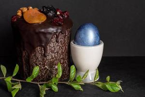 Osterkuchen und farbige Eier auf schwarzem Hintergrund. Feiertagsessen und Osterkonzept. foto