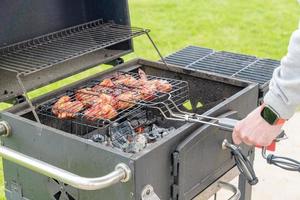 Junger Mann gekocht auf Mangal gegrillte Hähnchenflügel mariniert in Topmat-Sauce im Freien. lokales Essen foto