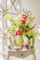 Ostern Innendekoration. schöne komposition mit kerzen, eiern, kaninchen, äpfeln und blühenden blumen auf weißem vintage-schrank. foto