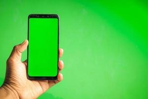 Hand, die Smartphone mit grünem Bildschirm hält foto