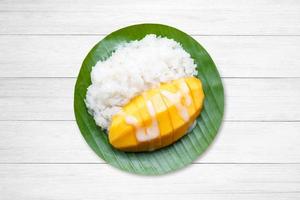 dessert süßer klebriger reis mit mango kokosmilch auf weißem holz foto
