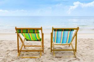 Strandkörbe am weißen Sandstrand mit bewölktem blauem Himmel foto