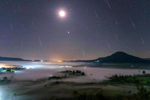 geminid meteor am nachthimmel mit mond und nebel am aussichtspunkt khao takhian ngo in khao-kho phetchabun, thailand foto