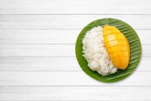 dessert süßer klebriger reis mit mango kokosmilch auf weißem holz foto