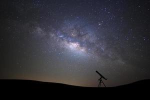 Silhouette des Teleskops, das die Wilky-Way-Galaxie mit Sternen und Weltraumstaub im Universum beobachtet foto