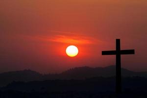 Silhouette des Kreuzes über dem Hintergrund des Sonnenuntergangs