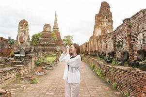junge schöne frau, die im thailändischen historischen park reist und fotografiert, ferien und kulturtourismuskonzept. foto