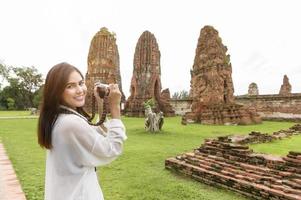 junge schöne frau, die im thailändischen historischen park reist und fotografiert, ferien und kulturtourismuskonzept. foto