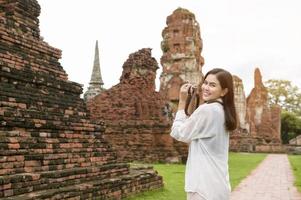 junge schöne frau, die im thailändischen historischen park reist und fotografiert, ferien und kulturtourismuskonzept. foto