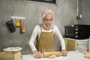 junge schöne muslimische frau backt in ihrer küche, bäckerei und cafégeschäft foto