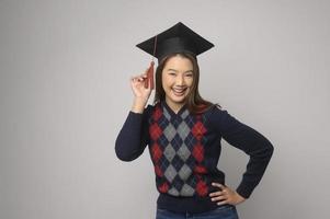 junge lächelnde frau, die abschlusshut, bildung und universitätskonzept hält foto