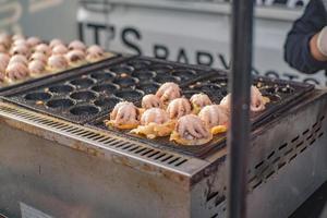 Riesenkraken-Takoyaki-Kochen auf Tako-Herd. Takoyaki, das berühmte japanische Straßenessen foto