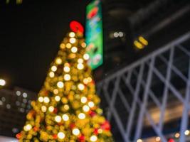 abstraktes unschärfefoto des weihnachtsbaums vor dem zentralen weltkaufhaus mit touristen, die am heiligabendtag spazieren gehen. stadt bangkok thailand foto