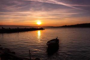 schöne Lichtkomposition und Stimmung des Bootes in ruhigem Wasser bei Sonnenuntergang foto