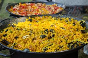 paella traditionelles spanisches essen. Paella, die auf einer großen Pfanne auf der brennenden Straße zubereitet wird foto